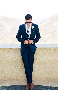 a man in a blue suit standing next to a wall