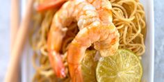 shrimp and noodles on a plate with limes, chopsticks and watermelon