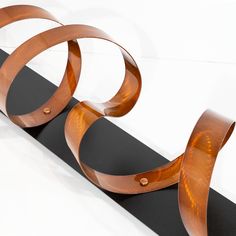 a sculpture made out of wood on top of a black board with two circular rings attached to it