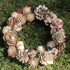 a wreath made out of pine cones and flowers on the grass with berries around it