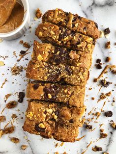 several pieces of bread sitting on top of a white counter next to a cup of peanut butter