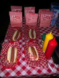 hotdogs and condiments are sitting on red checkered tableclothed tables