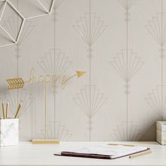 a desk with a notebook, pen holder and an arrow on it in front of a wallpapered background