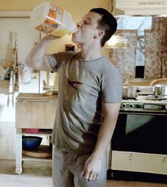 a young man drinking from a bottle in the kitchen