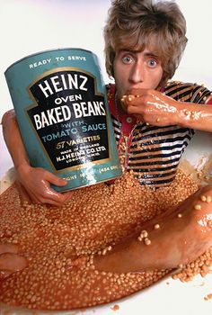 a man holding a can of heinz's baked beans in front of his face