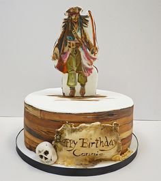 a birthday cake with a pirate figure on top and a skull in the foreground