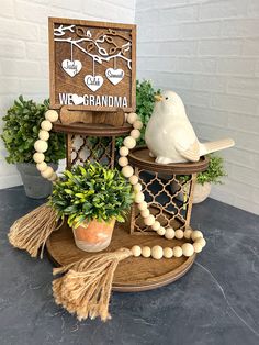 a wooden sign sitting on top of a table next to a potted plant and bird