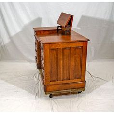 an old fashioned wooden cabinet on wheels with a small drawer in the middle and one door open