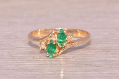 This stunning piece, known as The Emerald Harmony, features two captivating marquise cut natural emeralds at its center. The emeralds are elegantly set in 14 karat yellow gold and are flanked by four round brilliant cut natural diamonds, adding a touch of sparkle and enhancing the ring's elegance. The ring is crafted in 14 karat yellow gold and is currently a finger size 6.25 but can be adjusted to any finger size for an additional charge upon request, ensuring a perfect fit. Love this piece, but don't have the money to spend right now?  We offer FREE layaway on every item in our shop.  With just 20% down, take one full year (interest-free) to pay off your new jewelry!  There are no hidden fees or charges, ever.  For more information on our layaway policy, please contact us. Each piece has Emerald Ring Vintage, Pretty Accessories, Emerald And Diamond Ring, Marquise Cut, Natural Emerald, Emerald Ring, Ring Vintage, Rings Statement, Round Brilliant