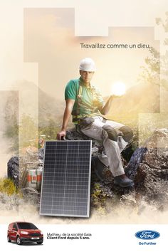 a man sitting on top of a rock next to a solar panel