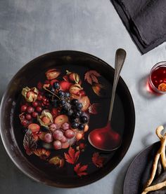 a bowl filled with fruit on top of a table next to other plates and utensils