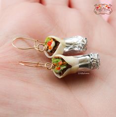 a pair of tiny food earrings sitting on top of a persons hand