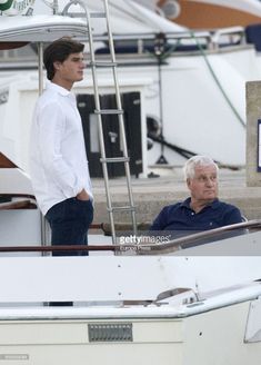 a man standing on top of a boat next to another man in a white shirt