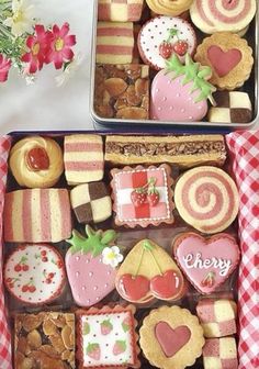 two tins filled with assorted cookies and pastries on top of a table