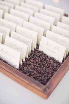 a wooden tray filled with lots of place cards on top of coffee beans next to each other