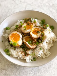 a bowl filled with rice and topped with hard boiled eggs on top of green onions