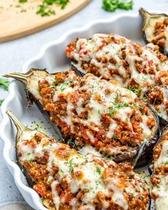 stuffed eggplant in a white dish with cheese and seasoning on the side