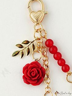 a red rose is attached to a gold plated keychain with beaded beads