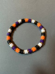 Orange, purple, black, and white clay bead bracelet with gold metal spacer beads.  Bracelet made with elastic string. Length is approx 7 inches unstretched.  Need a different size? Message me for custom options! Clay Needs Bracelets, Fall Loom Bracelet, Halloween Braclets Idea, Halloween Jewelry Diy Bracelets, Preppy Halloween Clay Bead Bracelets, Clay Beads Ideas Halloween, Halloween Beaded Bracelet Ideas, Bracelet Ideas For Halloween