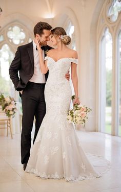 a bride and groom posing for a photo in front of an ornate archway with windows