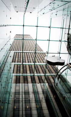 looking up at the side of a tall building with glass panels on it's sides