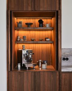 a wooden cabinet with coffee maker, cups and other items on it's shelves