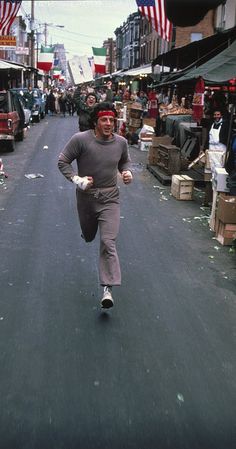 a man is running down the street with an american flag in the backgrund