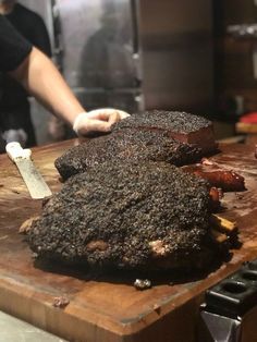 a person cutting up some food on top of a wooden board in a kitchen with an oven