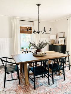 a dining room table with black chairs and a potted plant on top of it