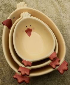 three bowls with red clay chickens sitting on top of each other in front of a carpeted area