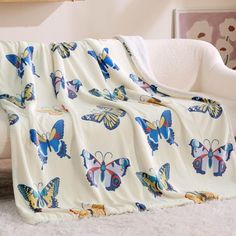 a white couch covered in a blanket with blue and yellow butterflies on it