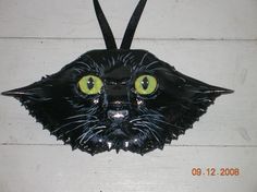 a black cat mask with yellow eyes is hanging on the side of a white wall