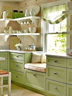 a kitchen filled with lots of green cupboards and counter top space next to a window