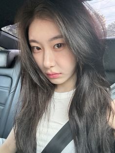 a woman with long hair sitting in the back seat of a car looking at the camera