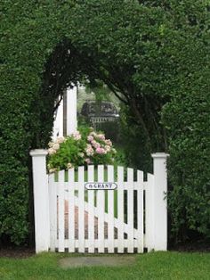 a white picket fence surrounded by green bushes