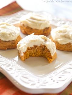 four pumpkin cookies with frosting on a white plate