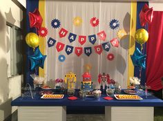 a birthday party setup with balloons, cake and decorations on a blue table clothed backdrop