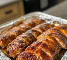 some meat wrapped in tinfoil on top of a pan filled with sauce and ketchup