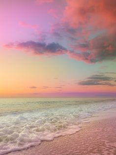 an ocean beach with waves coming in to shore and the sun setting on the horizon