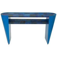 a blue console table with metal legs and an abstract design on the top, against a white background