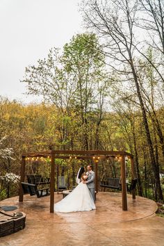 a bride and groom standing under a gazebo at their outdoor wedding ceremony in the woods