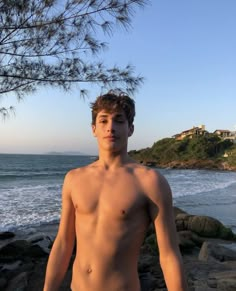 a shirtless young man standing next to the ocean