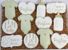 decorated baby shower cookies in a box with congratulations messages on the top and onesuits