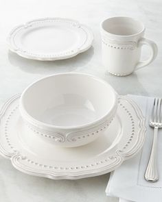 a white dinner set with silverware and napkins on a marble tableclothed surface