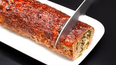 a knife is cutting into a meatloaf on a white plate with black background