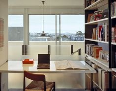 an open laptop computer sitting on top of a desk next to a book shelf filled with books