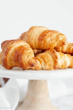 croissants on a white cake plate with other pastries