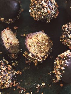 chocolate covered desserts with nuts and sprinkles on a black surface