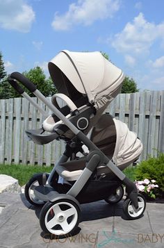 a baby stroller sitting on top of a cement ground next to a wooden fence