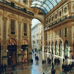 people are walking around in the middle of an indoor shopping mall with glass roofing